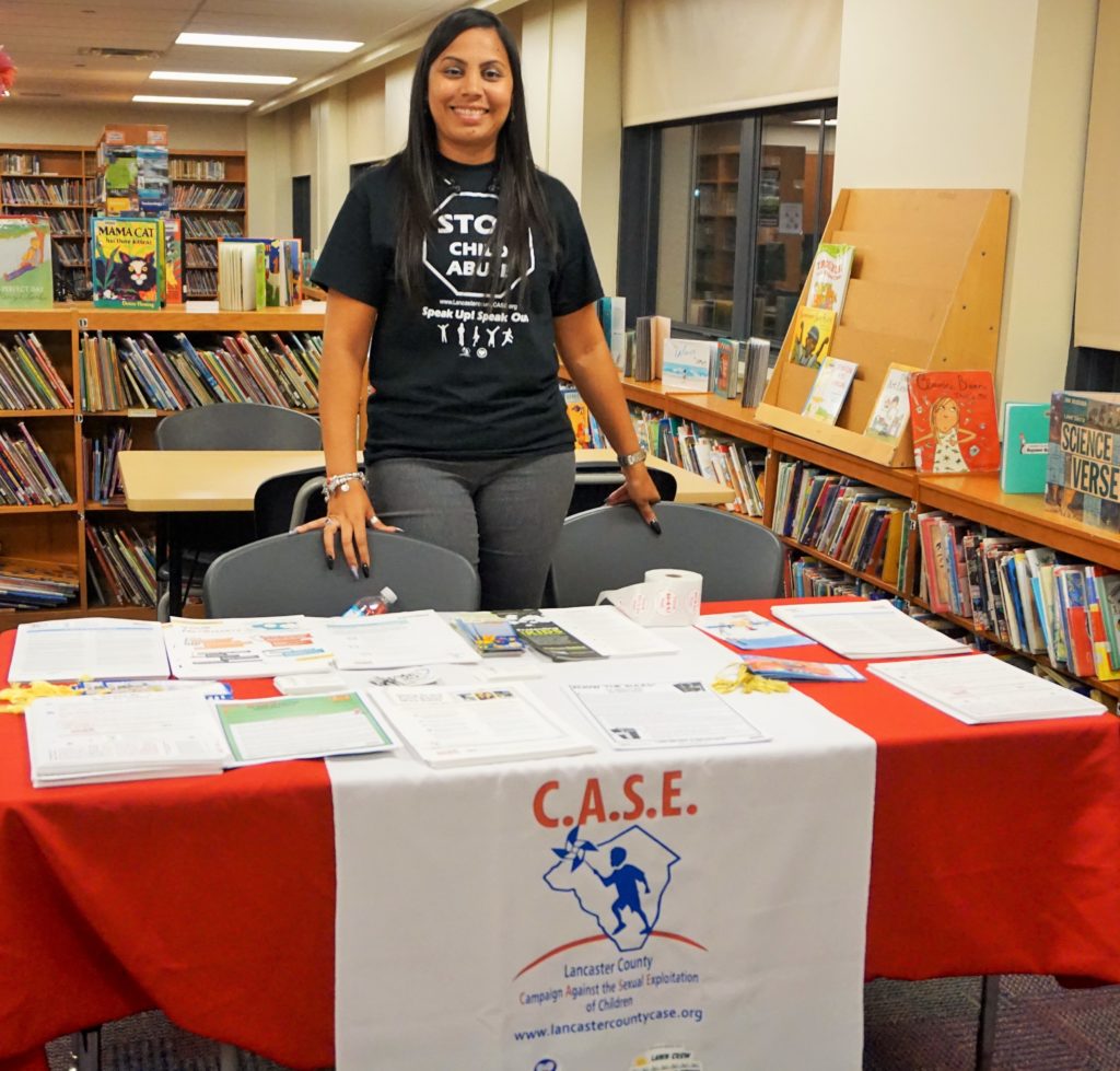Woman standing at C.A.S.E. information table in school library